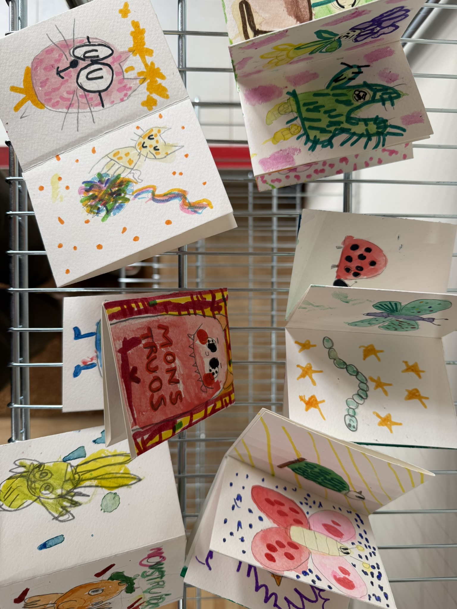 Dibujos infantiles desplegados sobre una rejilla en el taller